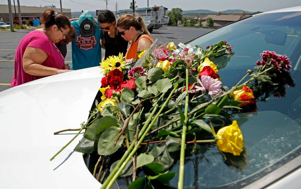 People pray next to a car believed to belong to a victim of a last night's duck boat accident,...